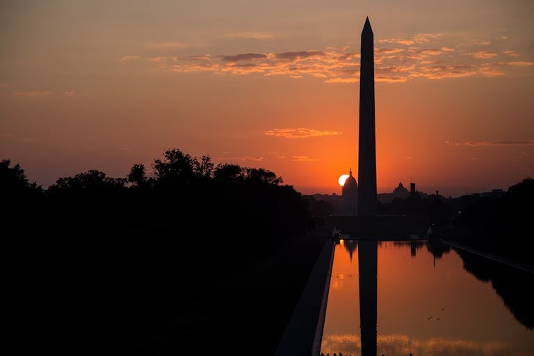 Captivating sunrise silhouette of the Washington Monument and reflection pool in Washington DC.