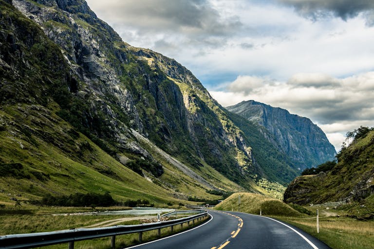 Curving highway through a dramatic Norwegian fjord landscape, perfect for travel enthusiasts.