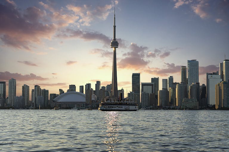 Stunning Toronto skyline at sunset, highlighting the CN Tower and waterfront from Lake Ontario.