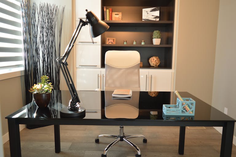 Stylish modern office workspace featuring a black desk, lamp, and white chair with shelving.