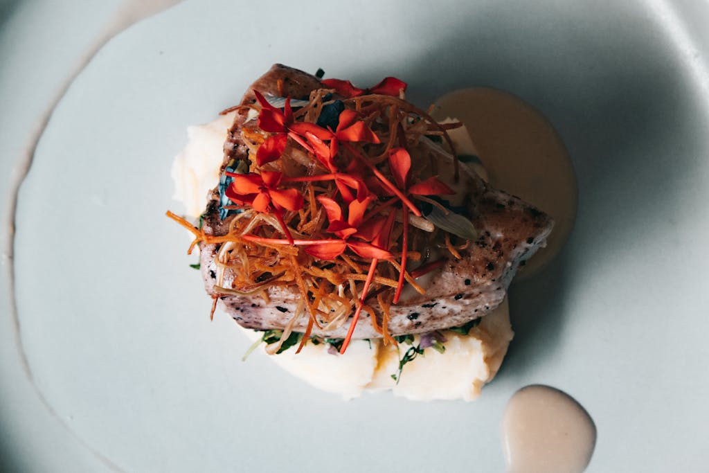 Top view of a gourmet dish with vibrant edible flowers, served on a minimalist plate.