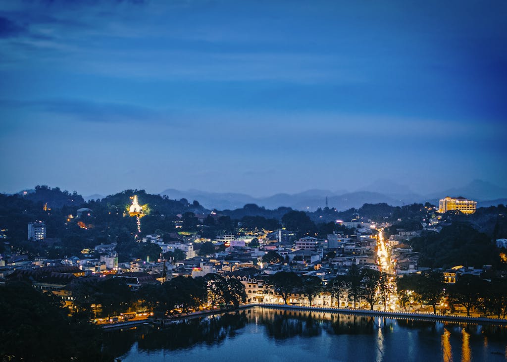 A beautiful aerial view of Kandy, Sri Lanka, at dusk with city lights reflecting on the lake.