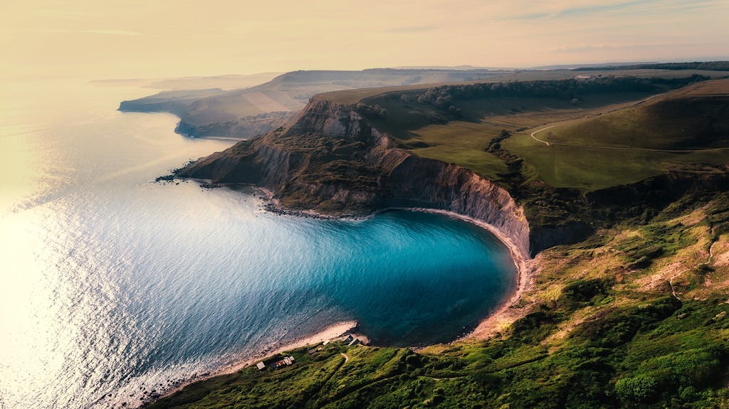 A breathtaking aerial view of coastal cliffs with turquoise water and lush landscapes.