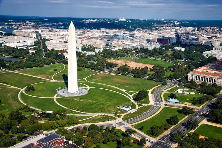 A breathtaking aerial view of the Washington Monument surrounded by cityscape and green landscapes.