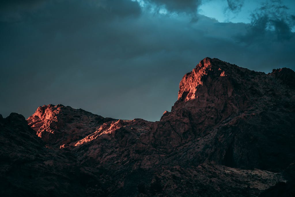 A breathtaking view of red-tinted mountainous peaks in Nevada under dramatic twilight skies.