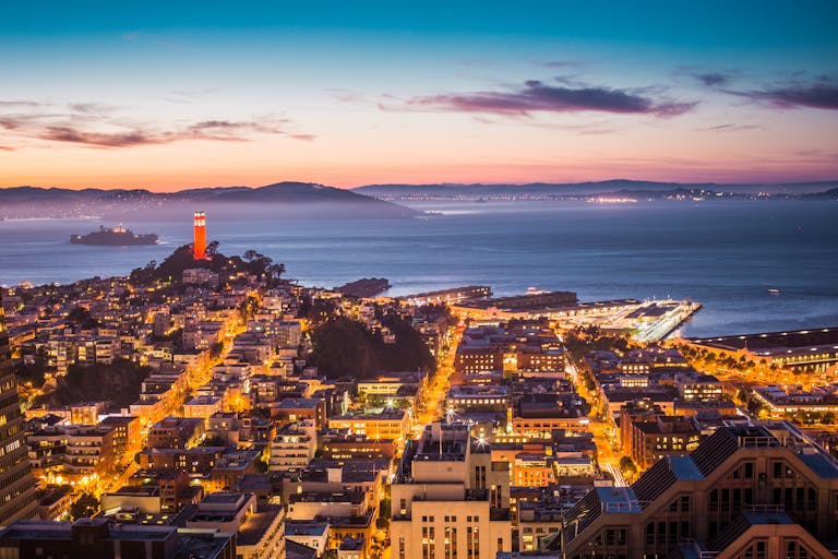 A breathtaking view of San Francisco's skyline and bay at dusk with city lights aglow.