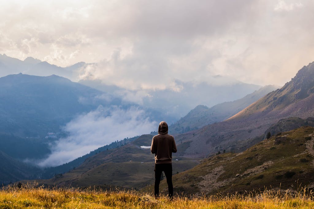 A lone hiker stands in awe of the misty mountain landscape in France.