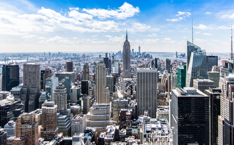 A stunning aerial view of New York City's skyline featuring the iconic Empire State Building under a bright blue sky.