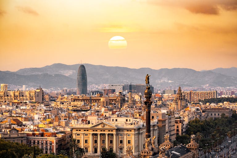 A stunning sunset view of the Barcelona skyline showcasing iconic landmarks and a warm, golden hour glow.