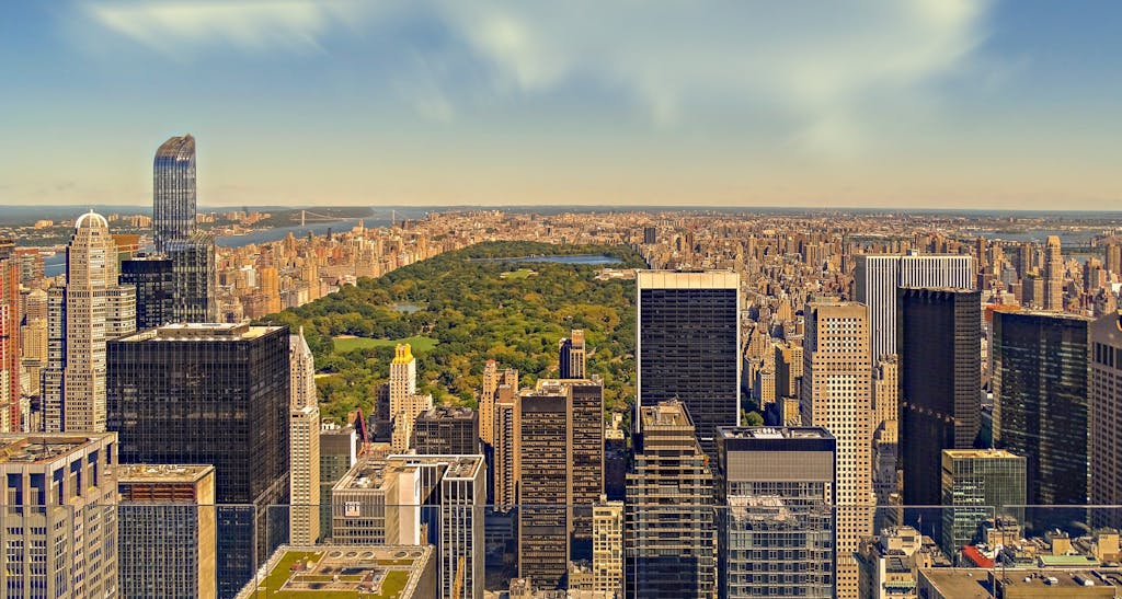 Aerial view of New York City skyline featuring Central Park amidst towering skyscrapers.