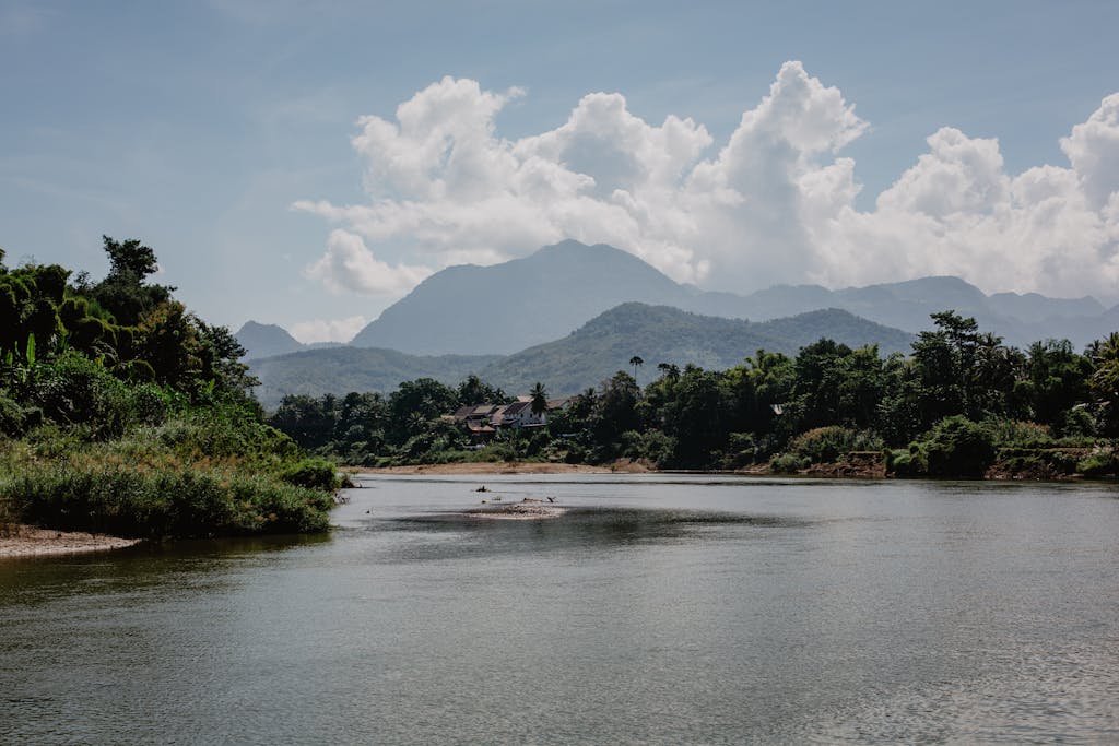 Amazing landscape of calm lake surrounded by tropical forest and high mountain ranges under beautiful cloudy sky