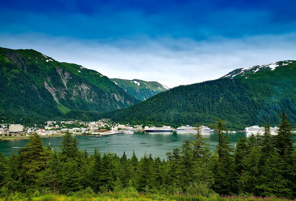 Beautiful coastal city with mountains and cruise ships under a clear blue sky.