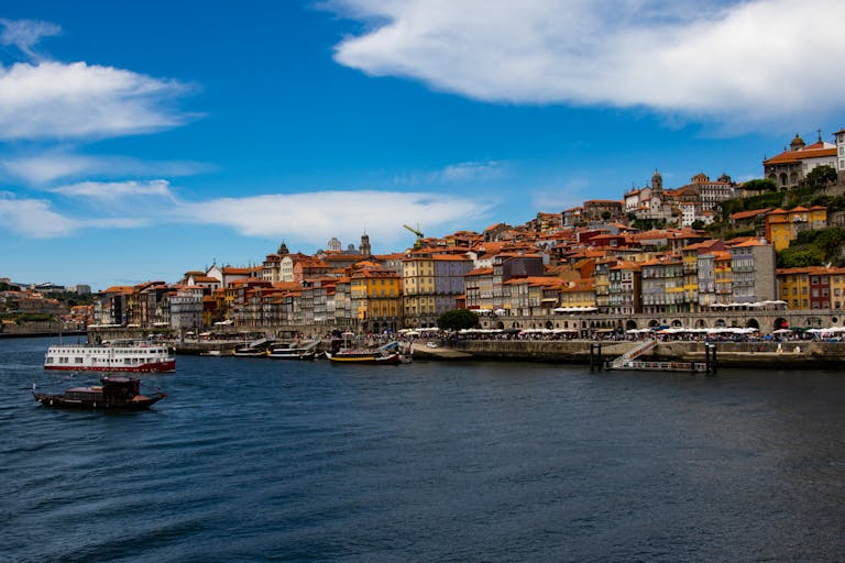 Beautiful panoramic view of Porto's riverside with colorful buildings and boats under a vibrant blue sky.