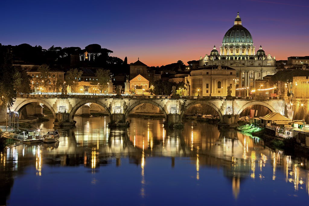 Beautiful view of Saint Peter's Basilica and St. Angelo Bridge in Rome at sunset reflecting in the Tiber River.