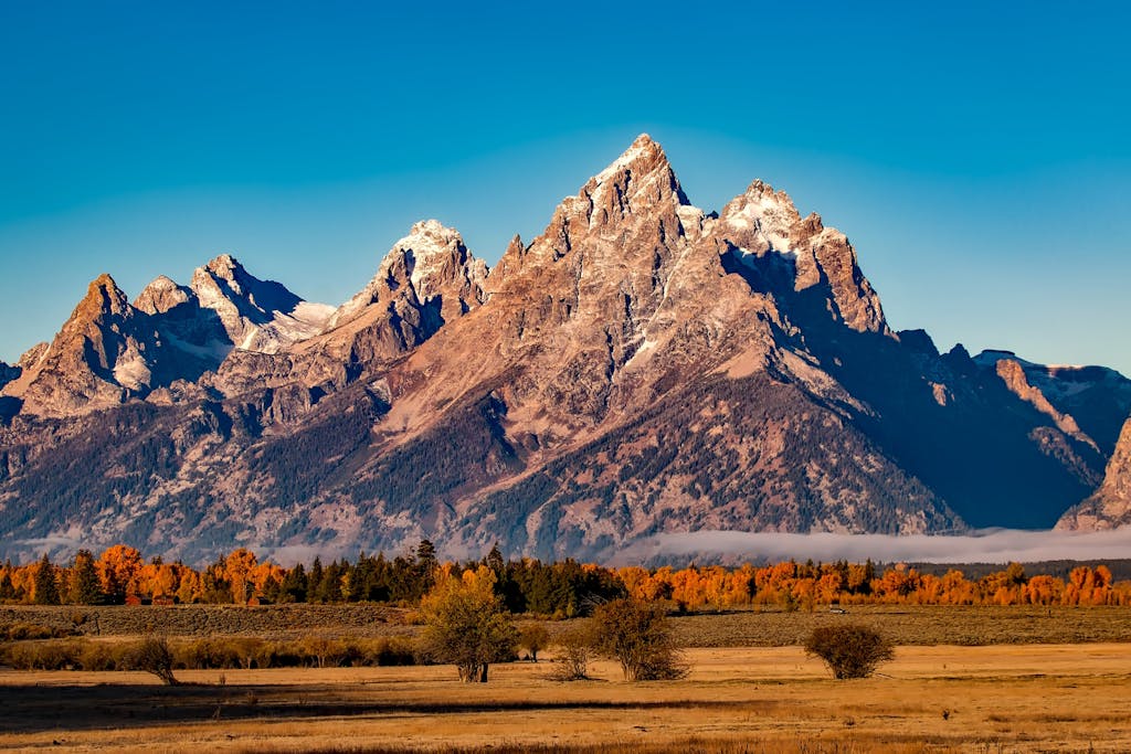 Breathtaking autumn landscape of Grand Teton with snow-capped peaks and colorful trees.