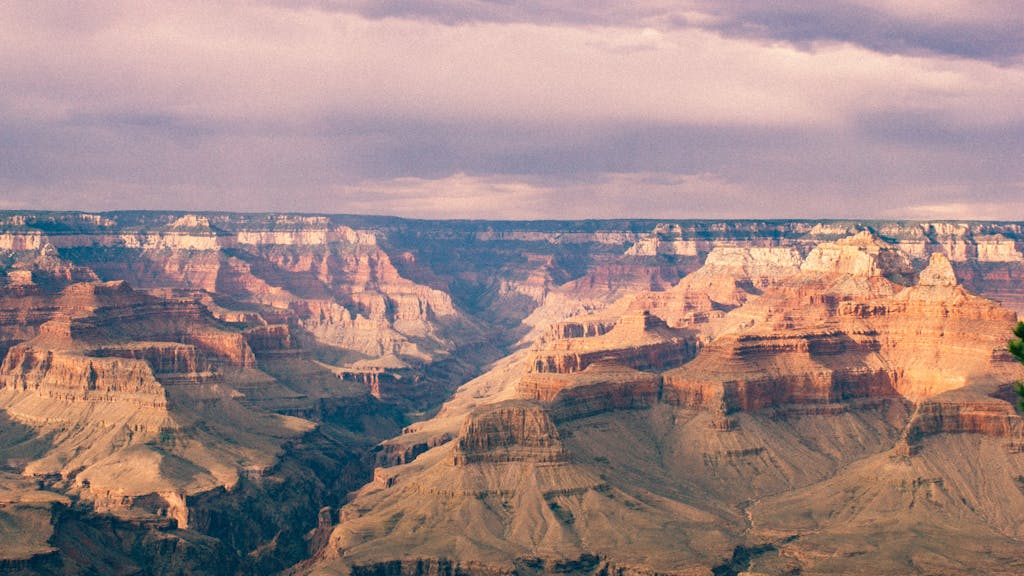 Breathtaking panoramic view of the Grand Canyon under a vibrant, cloudy sky.