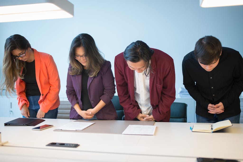 Business meeting with a diverse team bowing in respect, symbolizing cultural cooperation.