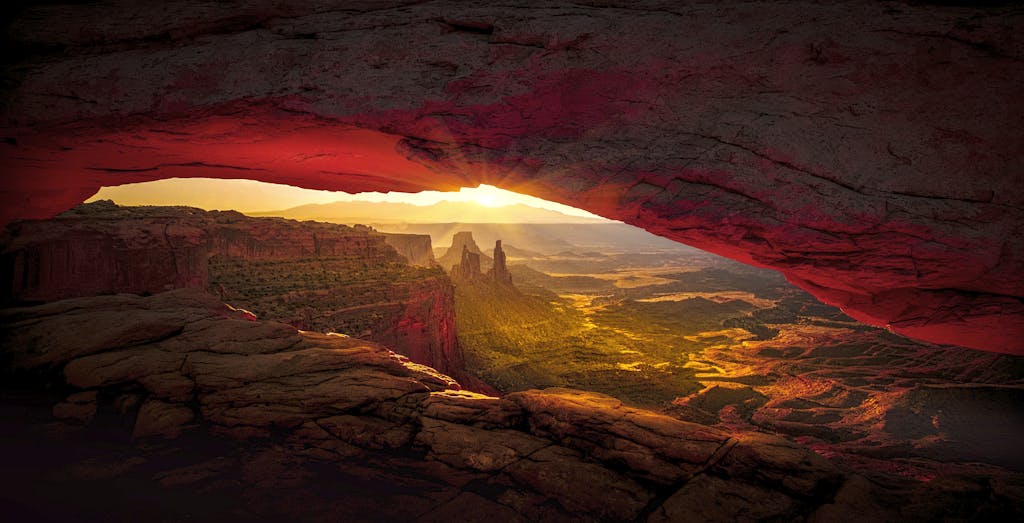 Captivating sunrise view through Mesa Arch in Canyonlands National Park showcasing vibrant desert landscape.