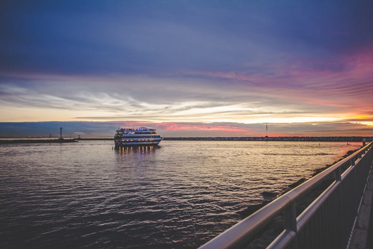 Cruise ship on the ocean during a beautiful sunset with calm water and vibrant skies.