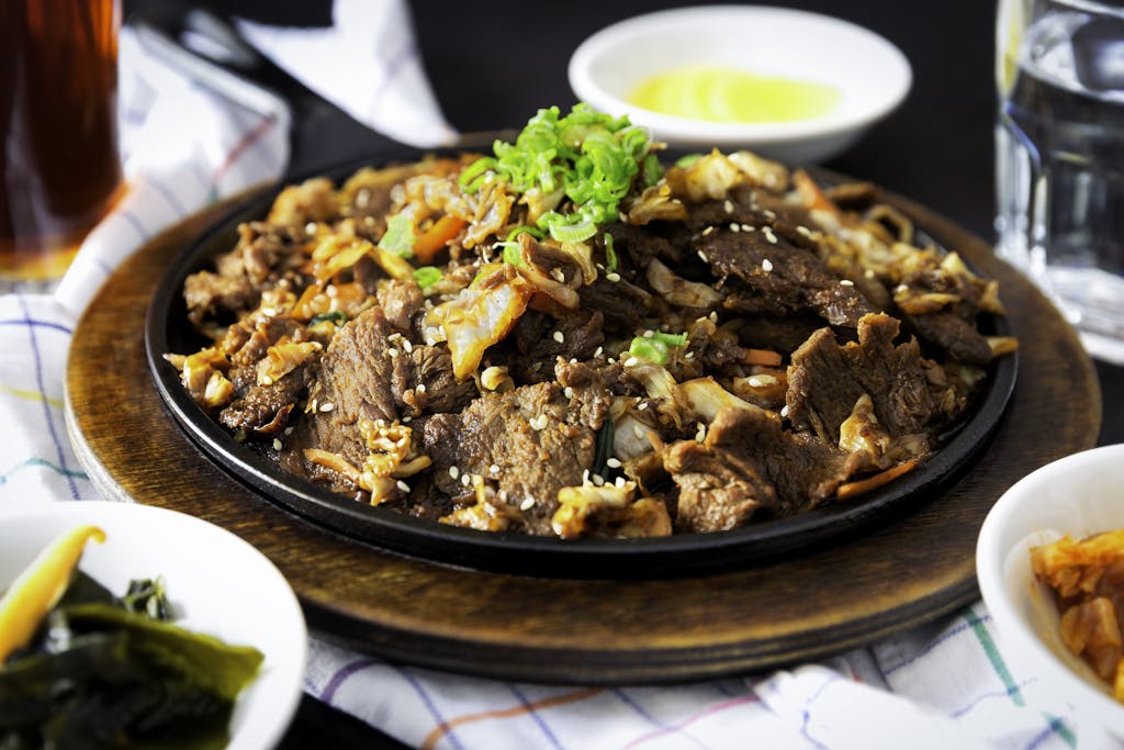 Delicious Korean BBQ beef dish with vegetables and sesame sprinkled on a hot plate.