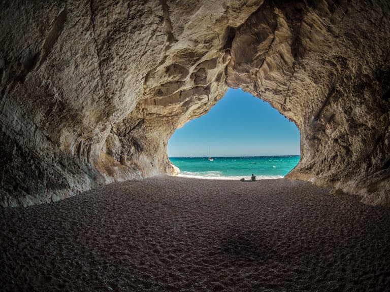 Discover a peaceful beach scene framed by a natural cave formation, perfect for relaxation.