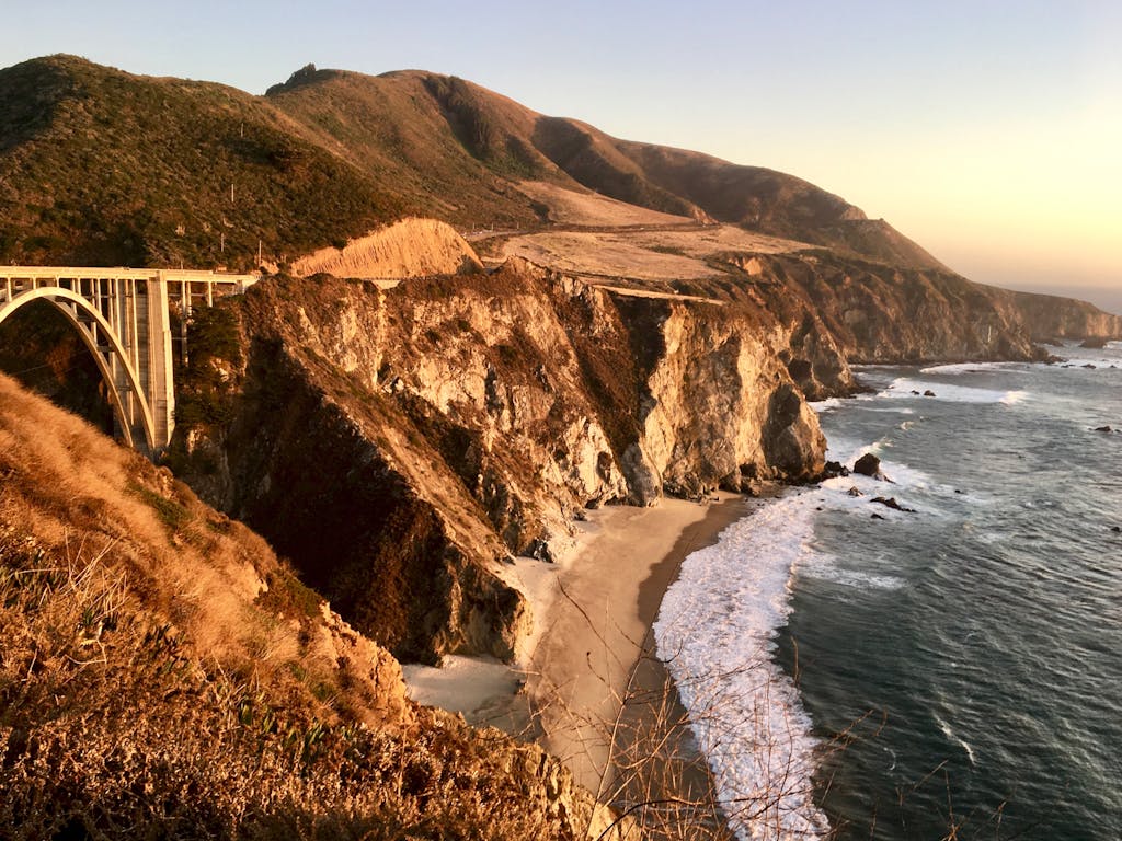 Dramatic cliffs along Bixby Creek Bridge on California's rugged coastline, captured at golden hour.