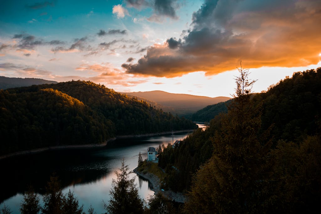 Dramatic sunset over a serene lake and lush hills in Cluj-Napoca, România.