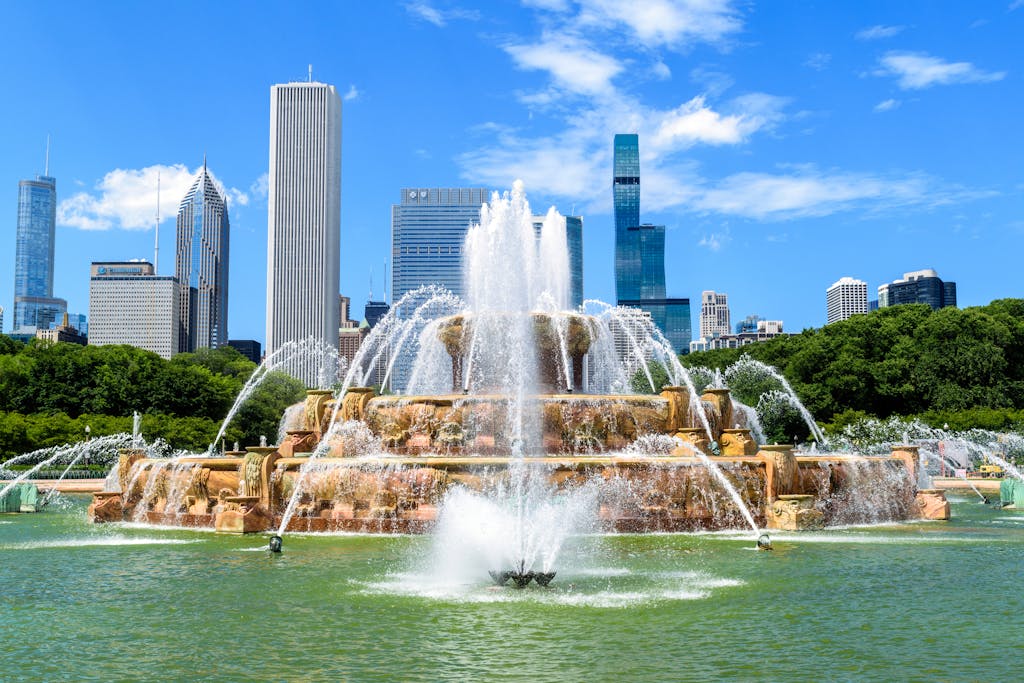 Dynamic view of Buckingham Fountain with Chicago skyscrapers under a bright blue sky.