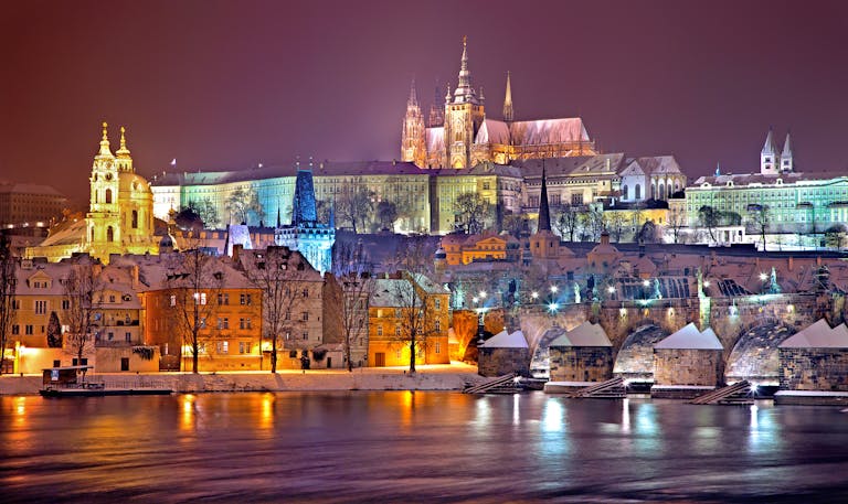 Illuminated Prague Castle and Vltava River at night in winter. Capturing historic beauty.