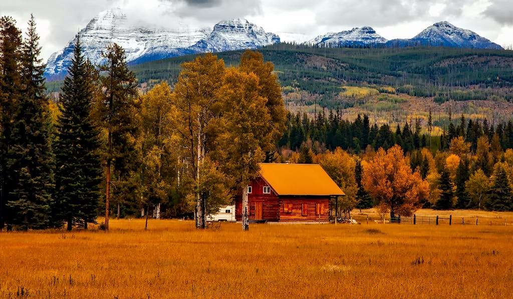 Picturesque cabin nestled in autumn landscape with mountain backdrop, ideal for serene retreats.