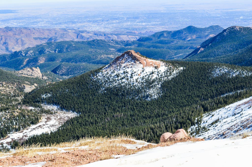 Stunning view of Pikes Peak with snow and lush green forests in El Paso County, Colorado.