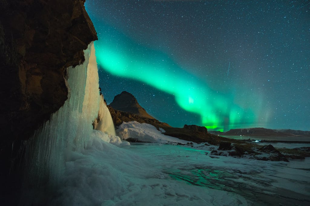 Stunning view of the Northern Lights over Kirkjufell mountain and frozen waterfall in Iceland. Perfect for nature lovers.