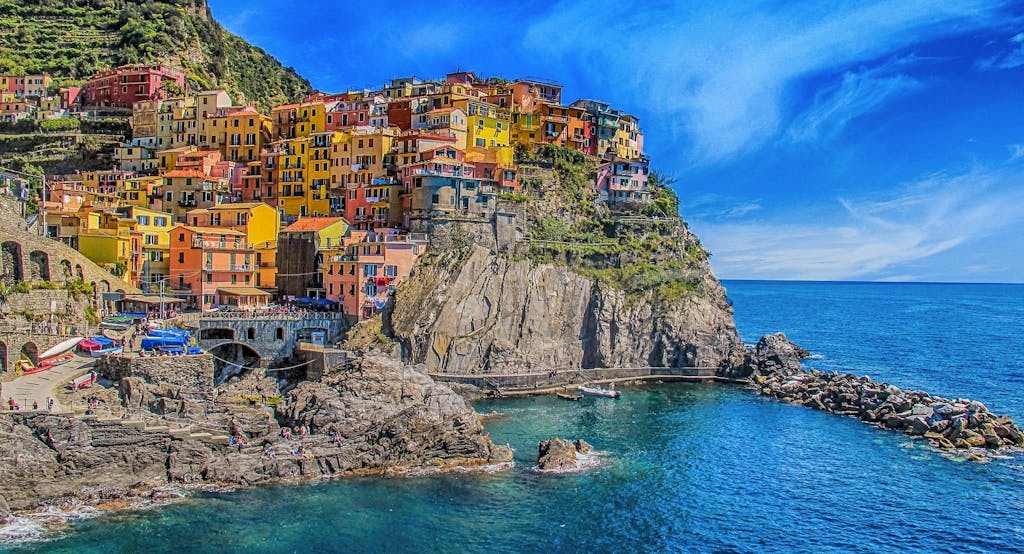 Vivid view of Manarola's colorful houses perched on cliffs, overlooking the blue sea.