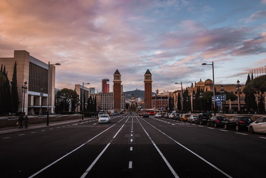 Wide street view in Barcelona featuring the iconic Venetian Towers at sunset.