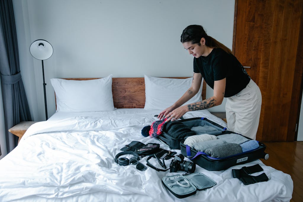 Young woman organizing luggage on a bed in a stylish indoor setting, preparing for travel.