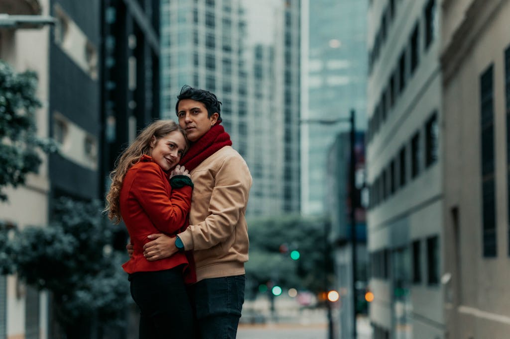 A couple warmly embracing on a city street with skyscrapers in Buenos Aires.