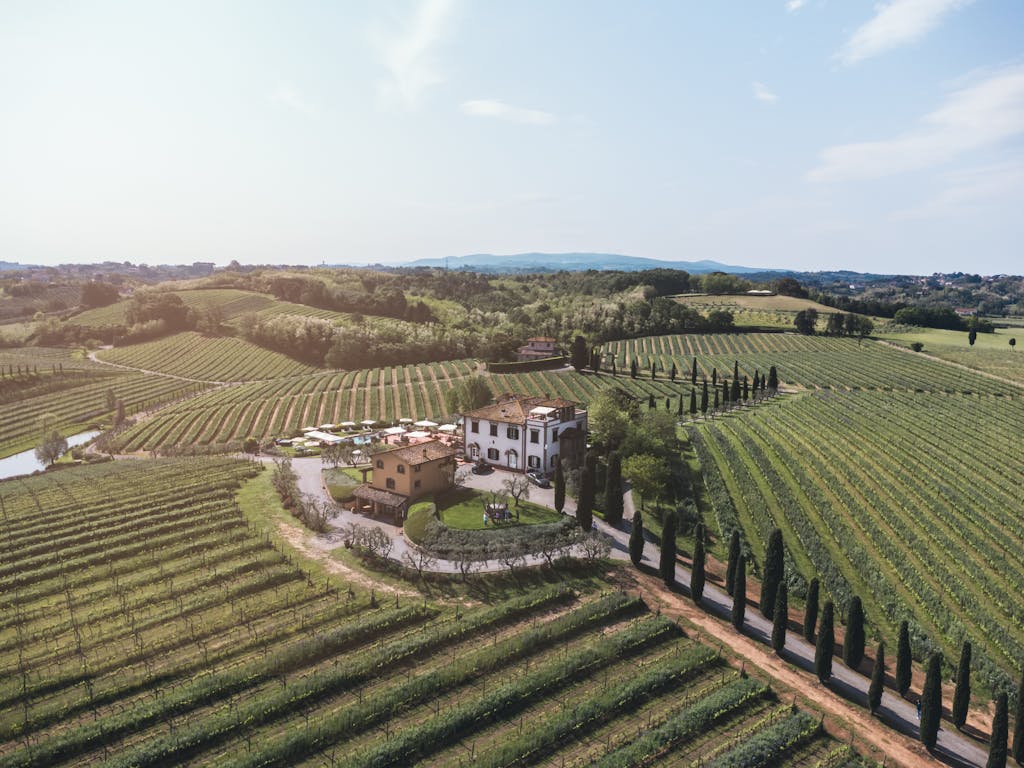 A picturesque aerial view of a villa amidst Tuscany's rolling vineyards, capturing serene countryside beauty.