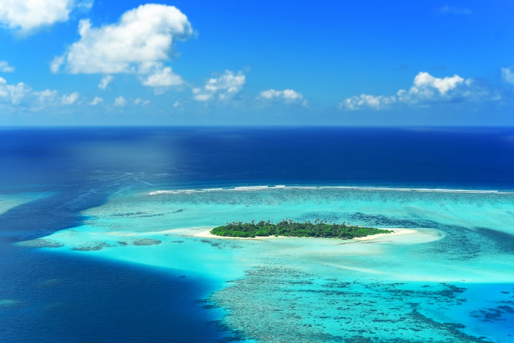 A stunning aerial view captures a lush island surrounded by turquoise waters in the Maldives.