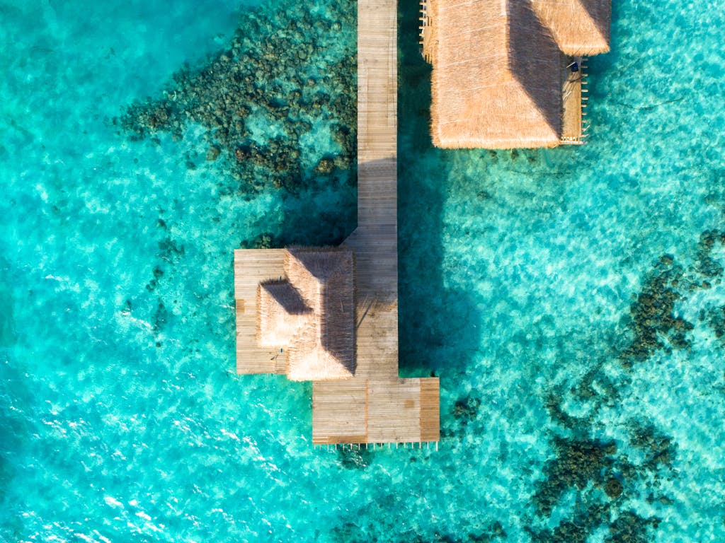 Aerial view of a tropical overwater resort with clear turquoise waters, ideal for vacation.