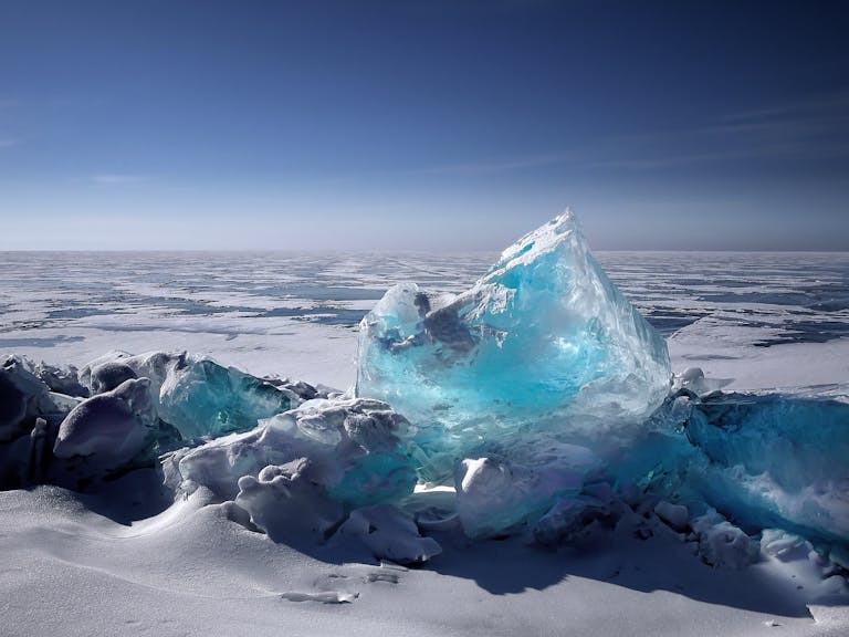 Captivating ice formation on a frozen lake under a bright blue sky during winter.