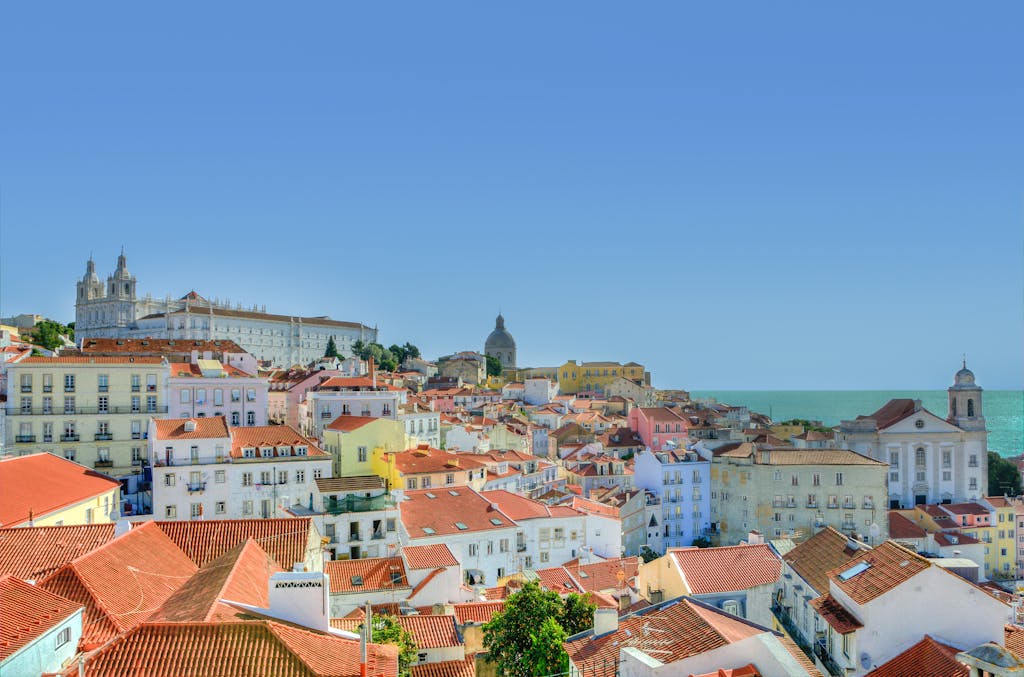 Captivating view of Lisbon's historic architecture with the Atlantic Ocean in the backdrop under a clear blue sky.