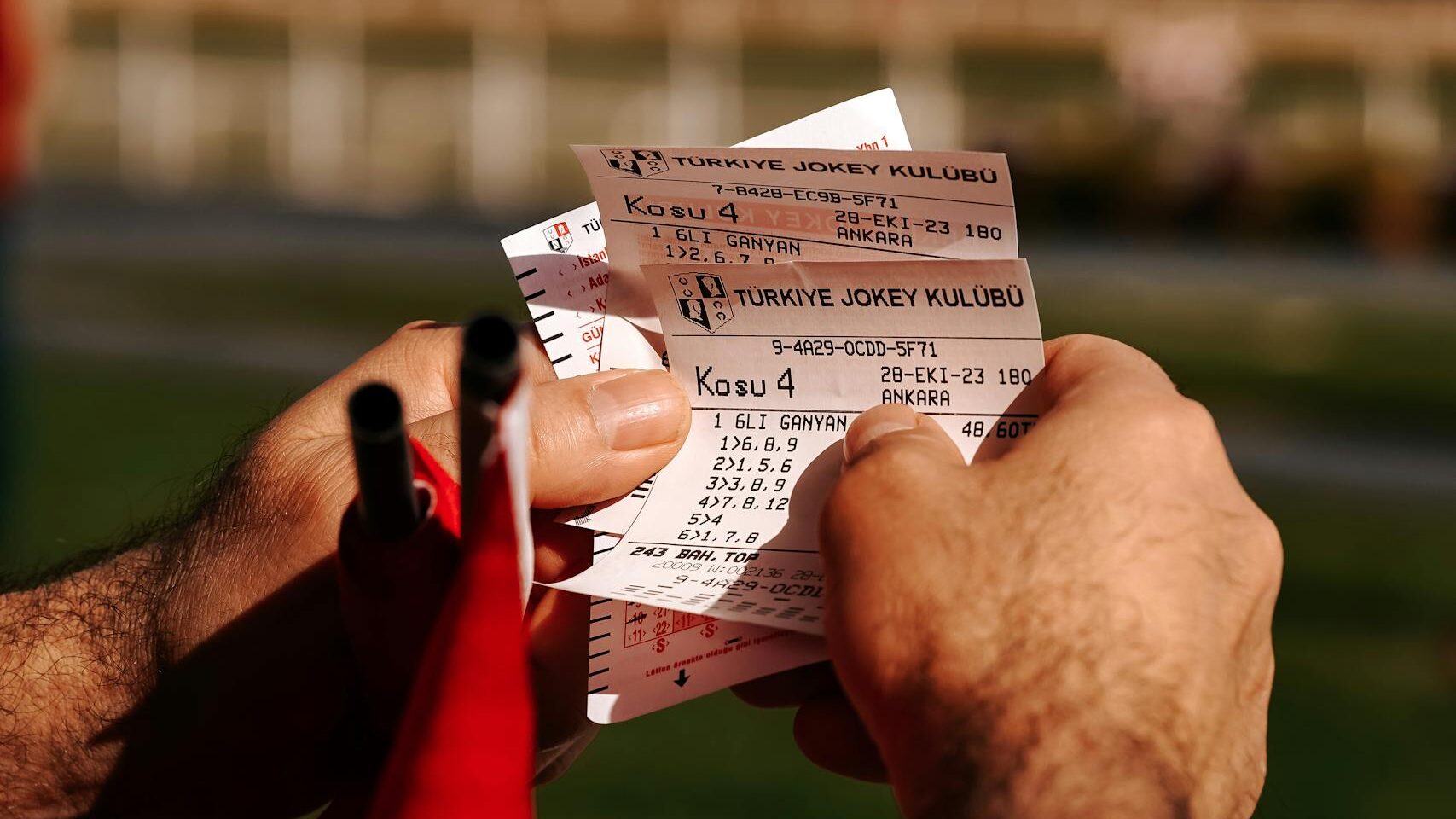 Close-up of a man holding horse racing tickets in Ankara, Türkiye. Vibrant outdoor setting.