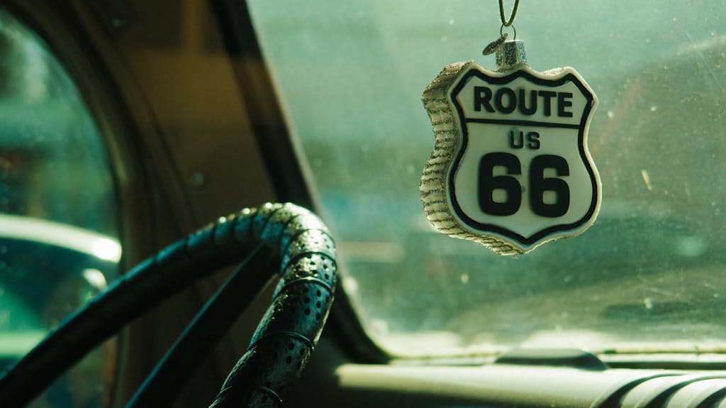 Close-up of Route 66 ornament hanging inside car with vintage steering wheel.