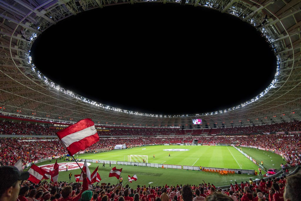 Exciting soccer match with enthusiastic fans in a packed stadium under bright lights.