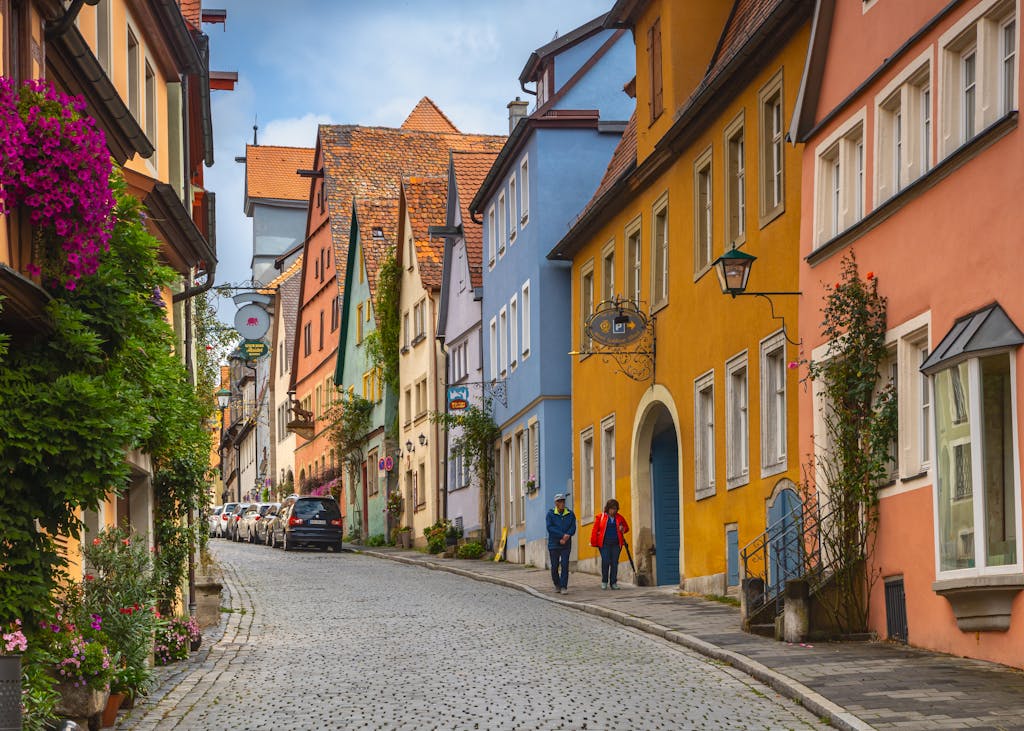 Explore a vibrant, cobblestoned street lined with colorful historic buildings in a charming European town.