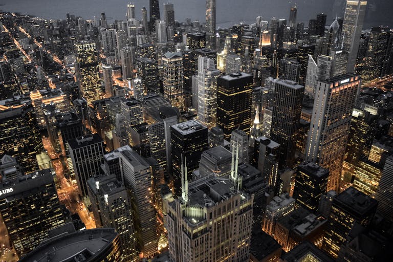 Explore the vibrant skyline of Chicago with its illuminated skyscrapers and bustling urban life captured at dusk.