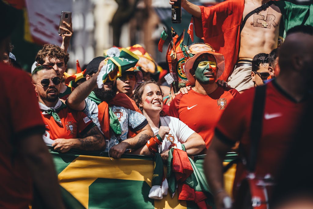 Joyful soccer fans in vibrant costumes celebrate outdoors during a sunny day.