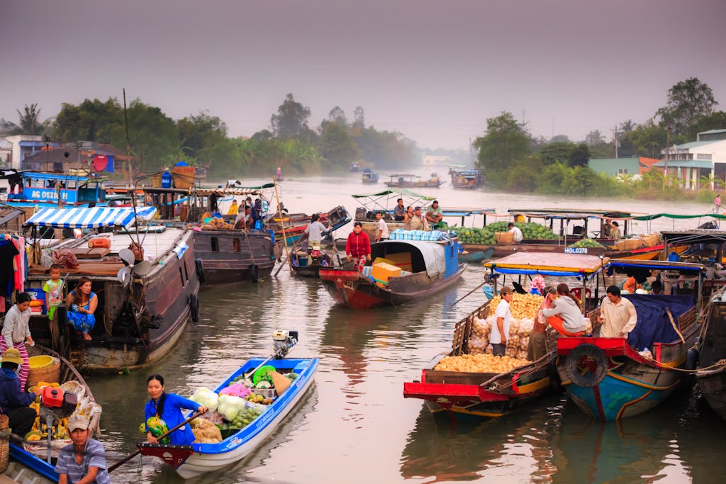 Lively floating market scene with locals trading fresh produce from traditional boats on a calm river.