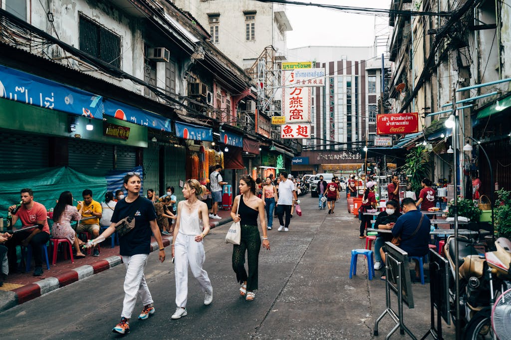 Lively scene in a Chinatown market street with people walking and dining.