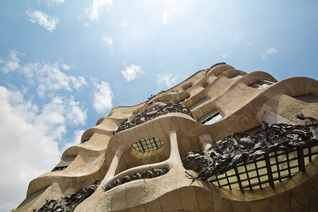 Low angle view of the Casa Milà's unique architectural facade against a vibrant sky.